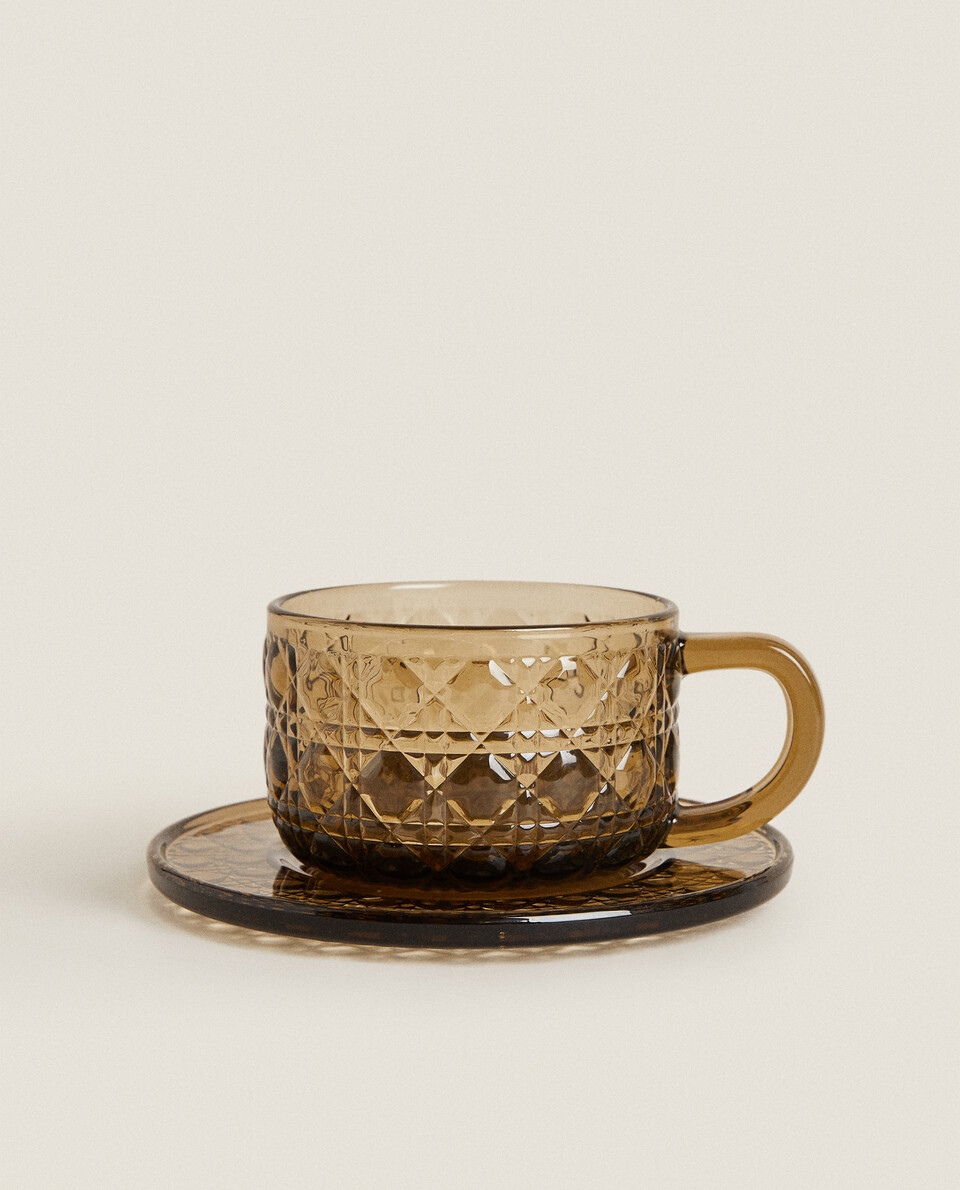GLASS TEACUP AND SAUCER WITH RAISED GEOMETRIC DESIGN